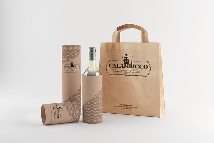 Realizzazione grafica Packaging L'Alambicco - Prodotti tipici trentini per bottiglie di vino a forma di cilindro di cartone naturale con richiamo texture biglietto da visita e ideazione shopper di carta con logo e indirizzo
